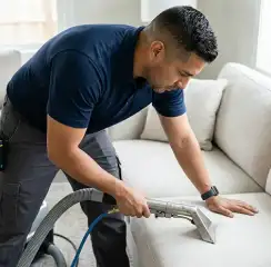 Professional upholstery cleaning technician using an extraction wand to deep-clean a fabric sofa, Kansas City, MO.
